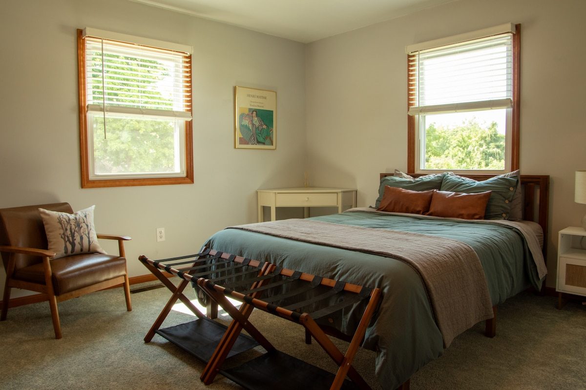 The first queen bedroom, with a reading chair and luggage rack